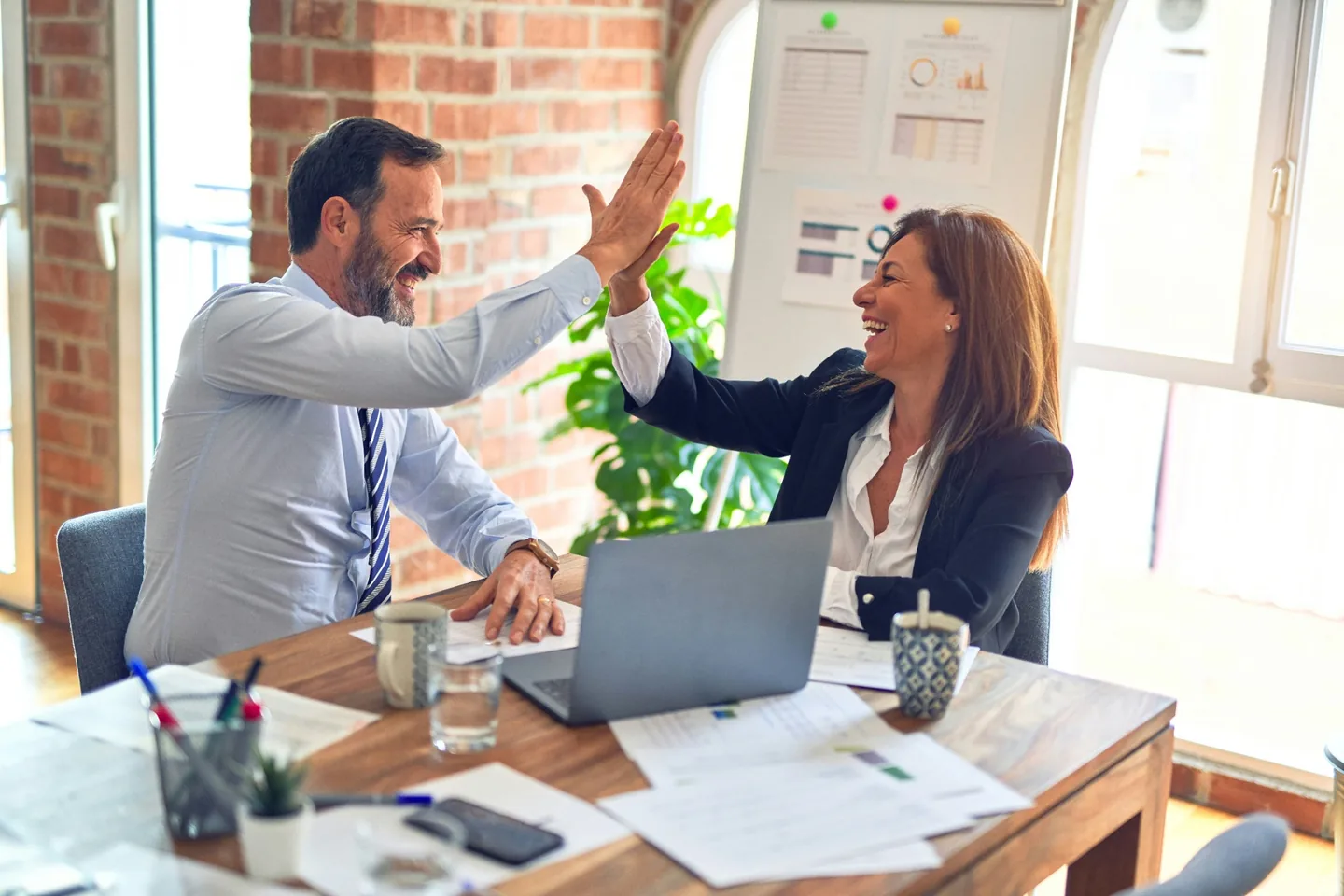 Two colleagues celebrating progress at a desk.